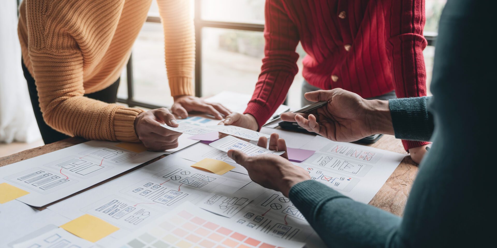creative designer team UI UX creative designer team designing wireframe layout for responsive mobile smartphone application in office.